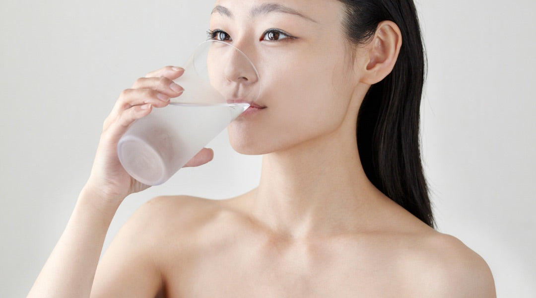 Young woman with beautiful skin drinking water from a glass