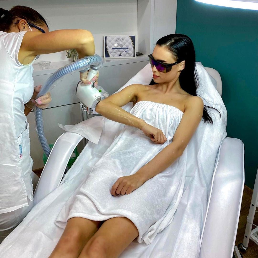  esthetician performs laser hair removal treatment on a woman’s arm